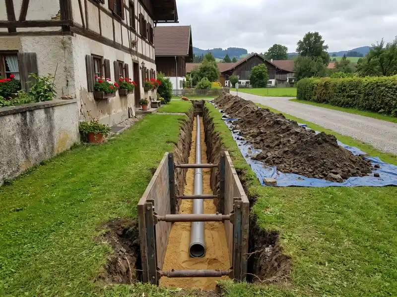 Gerader Graben vom Haus zur Straße, Abwasserrohr im Sandbett, Verbau im Graben
